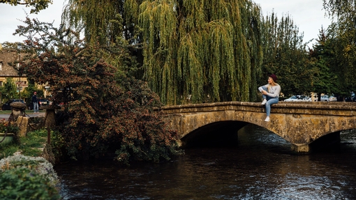 Blond woman wearing hat and jeans sitting on bridge