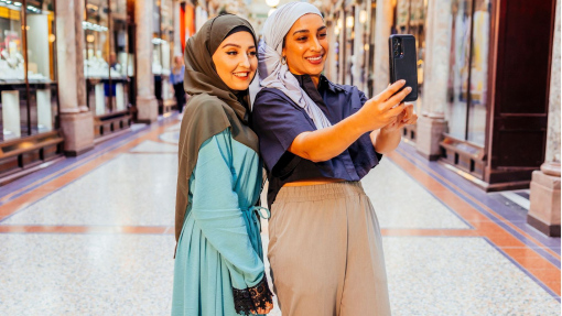 Two women take a picture together in an indoor shopping arcade