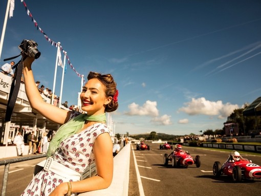 Woman taking a selfie in vintage dress standing by a car racing track