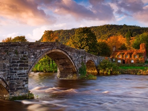 Large stone arched bridge over a flowing river. Sunset