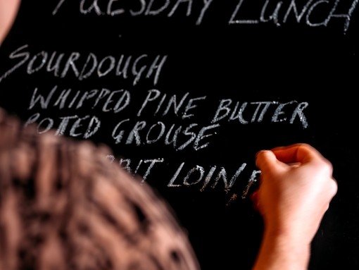 Close up of human hand writing menu on blackboard