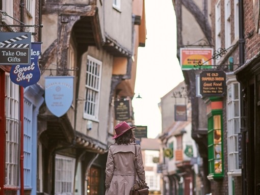 Woman wearing pink hat walking through narrow street