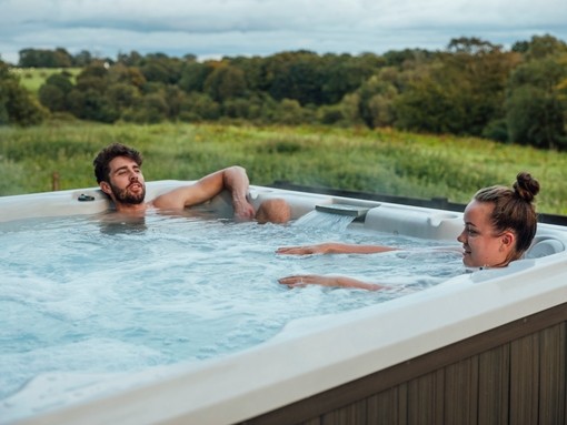 Couple relaxing in a hot tub overlooking countryside