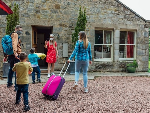 Family arriving at the exterior of a Bed and Breakfast home, met by host