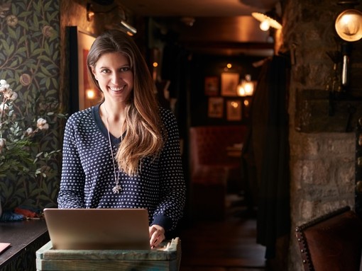 Female receptionist smiling at the camera working on laptop at Hotel check in