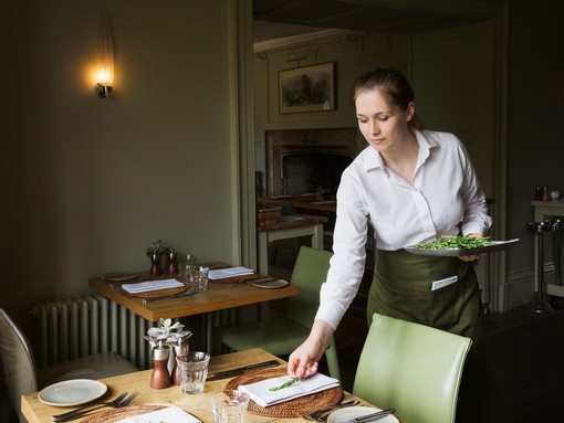 Woman in apron setting table in a restaurant