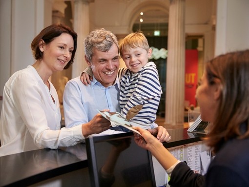 Family buying entry tickets from a museum reception