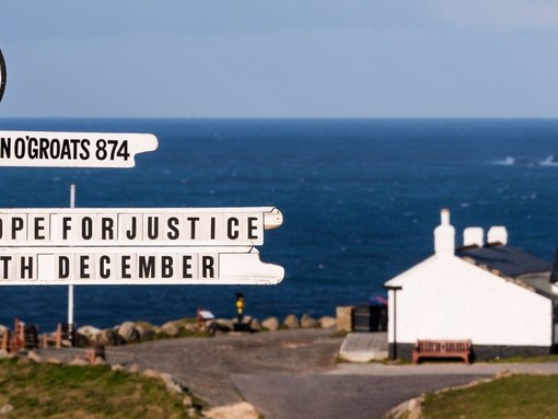 White painted signpost on a clifftop at Lands End. White building