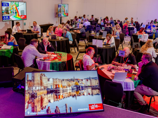 A room filled with attendees sat at tables at a business event