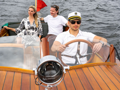 A man and a woman on a boat driven by a skipper on a lake