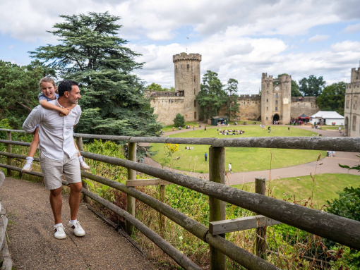 Father carrying his daughter, smiling and exploring the grounds of a castle