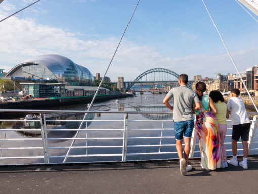 Family standing on a bridge overlooking a city river