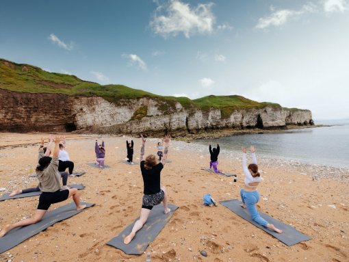 A group of people practising yoga on a beach