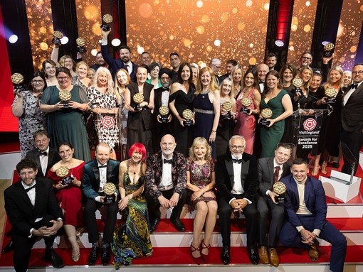A group of winners on stage holding their awards at a gala ceremony.