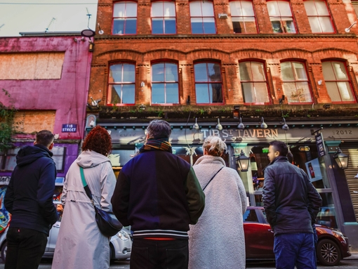 People in a street looking at city buildings on a walking city food tour.