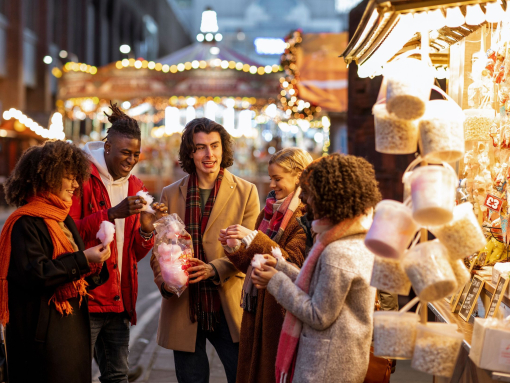 Group of young friends sharing a bag of cotton candy at the Christmas market.