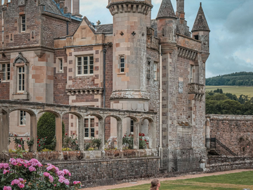 A woman twirling her dress in the gardens of a stately mansion.
