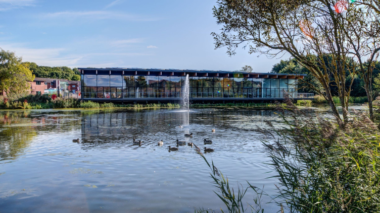 View of lake complete with fountain and ducks to a glass fronted building