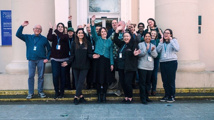 A group of people assembled outside of a building smiling