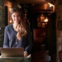 Female receptionist smiling at the camera working on laptop at Hotel check in
