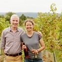 Couple standing in a vinyard holding wine
