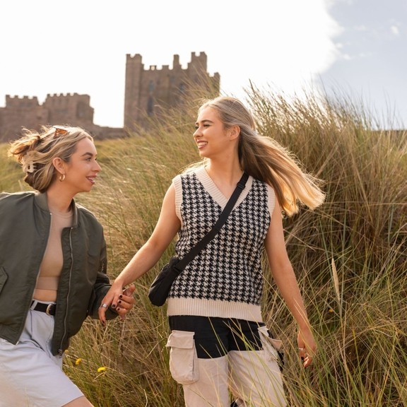 A couple walking in the sand dunes near Bamburgh Castle