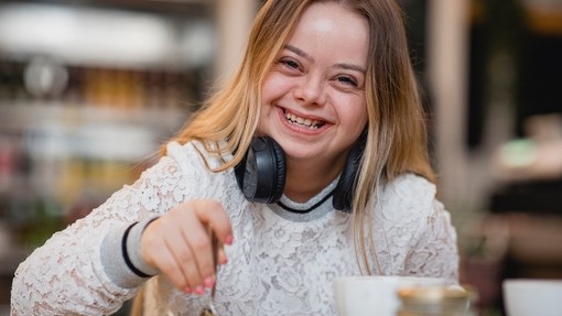 Young female with Downs Syndrome sat at a table laughing
