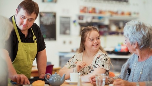 A person with Downs Syndrome serving customers in the cafe