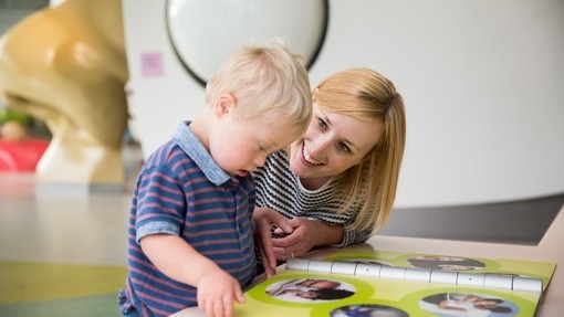 Young blonde boy with Downs Syndrome looking through a book
