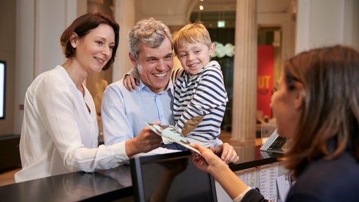 Family buying entry tickets from a museum reception