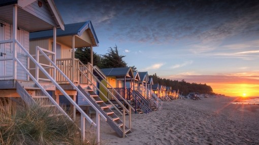 Sunset at high tide behind the old beach huts on coast