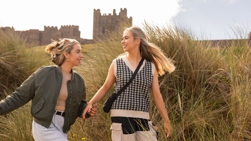 A couple walking in the sand dunes near Bamburgh Castle