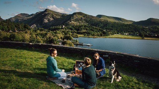 Friends having a picnic in grassland by a glacially formed lake.