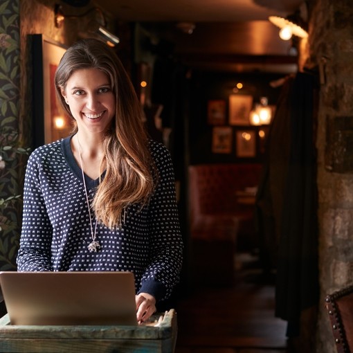 Female receptionist smiling at the camera working on laptop at Hotel check in