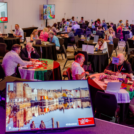 A room filled with attendees sat at tables at a business event