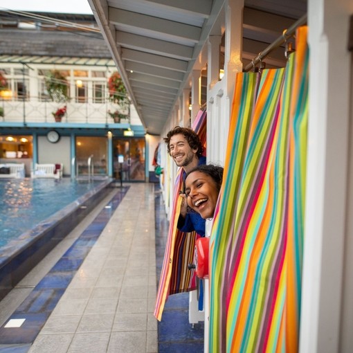 Man and woman peek out of changing rooms before going for a swim
