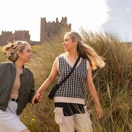 A couple walking in the sand dunes near Bamburgh Castle