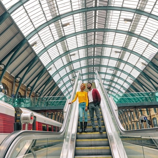 A couple travel down an escalator at a train station