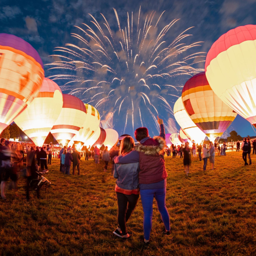 Lit up hot air balloons and fireworks in the night sky