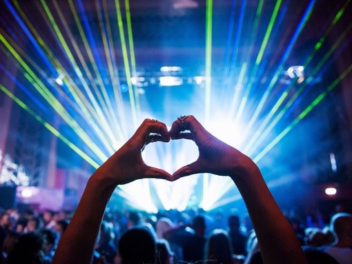 Woman making heart shape with hands at music event. UK
