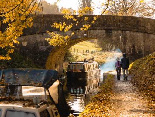 Man and woman walking beside a canal near a low bridge