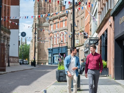 Two men walking past shops and restaurants