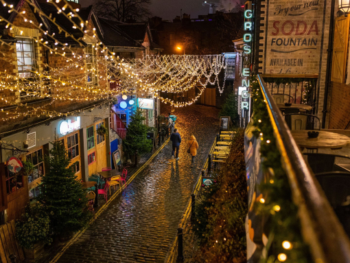 Rows of fairy lights draped over a cobbled street at night