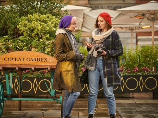 Two young women walking and talking in Covent Garden piazza