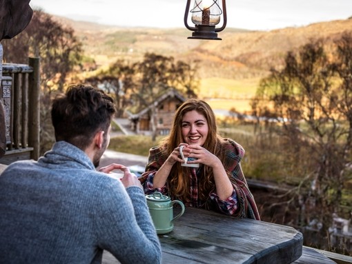 A couple seated, overlooking valley, having a hot drink