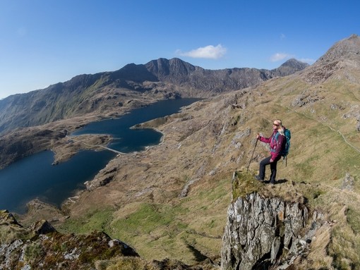 Woman standing on a rock, high above the lake in a valley