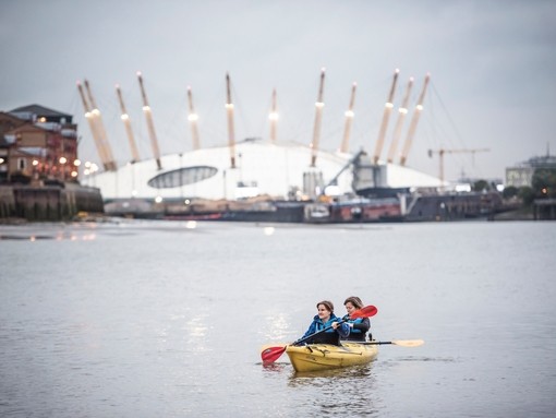 Two girls kayaking on the river in front of the O2 arena