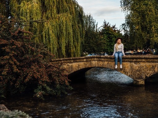 Blond woman wearing hat and jeans sitting on bridge