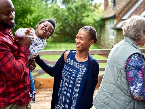 Father holding son with mother laughing in rural setting