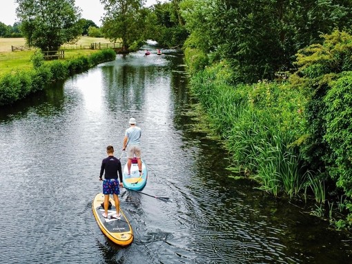 Two men paddle boarding on Dedham river